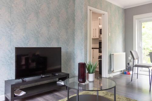 a living room with a tv and a glass table at Croftspar House in Glasgow