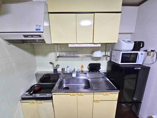 a small kitchen with a sink and a microwave at ZEUS choice FUKUOKA in Fukuoka