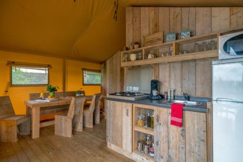 聖于連－德朗德的住宿－Camping Village de la Guyonnière，一间带木墙和冰箱的厨房和用餐室