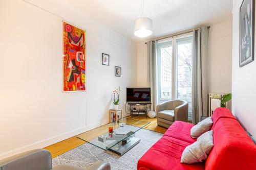 un salon avec un canapé rouge et une table en verre dans l'établissement GuestReady - A humble home in Auteuil, à Paris
