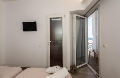 a white room with a mirror and a bed and a window at Olympia in Mýkonos City