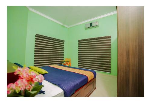 a green bedroom with a bed with a vase of flowers at Gilead Holliday in Tāmarakulam