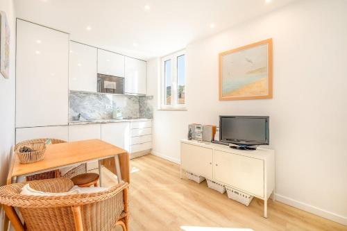 a kitchen with white cabinets and a tv on a table at GuestReady - The Atlantique retreat in Sesimbra