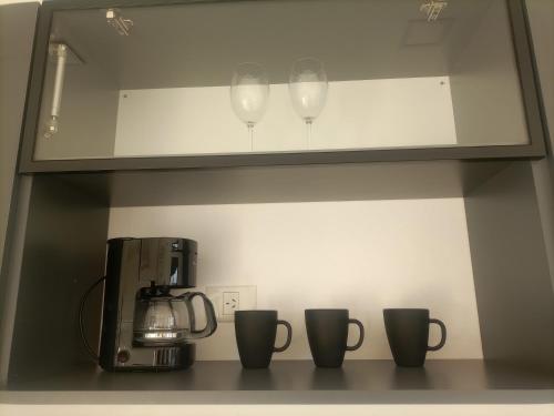 a shelf with three wine glasses and a coffee maker at Alka hermoso y cómodo departamento in Morón