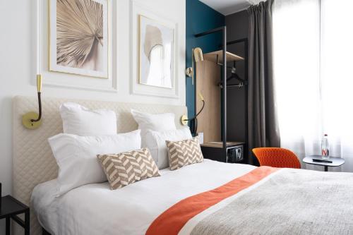 1 dormitorio con 1 cama blanca grande con almohadas en Hôtel D'Anjou, en Angers
