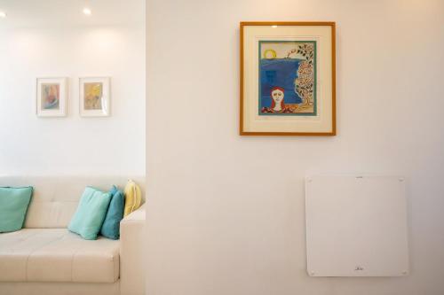 a living room with a white couch and paintings on the wall at GuestReady - The Atlantique retreat in Sesimbra