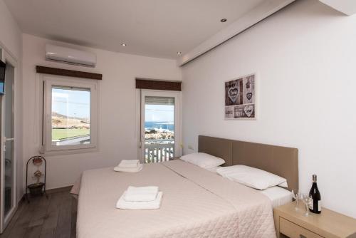a white bedroom with two beds and two windows at Olympia in Mikonos