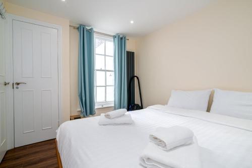 um quarto com uma grande cama branca com toalhas em GuestReady - Fantastic Apt near Regent's Park em Londres