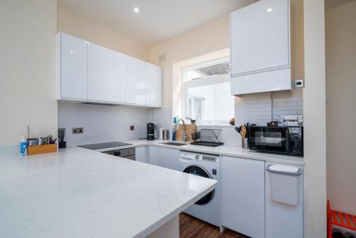 uma cozinha com armários brancos e um balcão branco em GuestReady - Fantastic Apt near Regent's Park em Londres