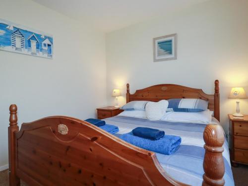 a bedroom with a large wooden bed with blue pillows at Summerfield Cottage in Gorran Haven