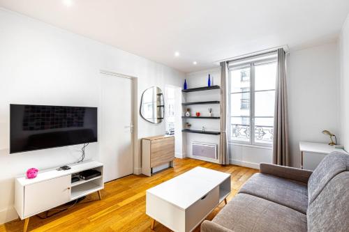 ein Wohnzimmer mit einem Sofa und einem TV in der Unterkunft GuestReady - Modern stay near the Pantheon in Paris