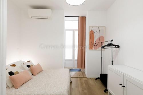Cette chambre blanche comprend un lit avec des oreillers roses. dans l'établissement August, à Cannes