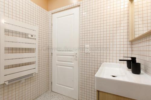 La salle de bains est pourvue d'un lavabo et d'une porte blanche. dans l'établissement August, à Cannes