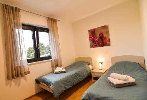 a bedroom with two twin beds and a window at Luxury apartment Punta with sea view and swimming pool in Premantura