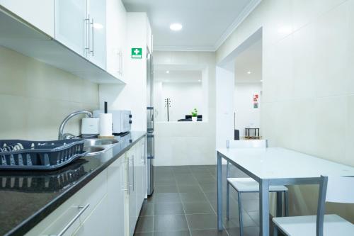 a white kitchen with a sink and a table at Avenida House 1 in Ponta Delgada
