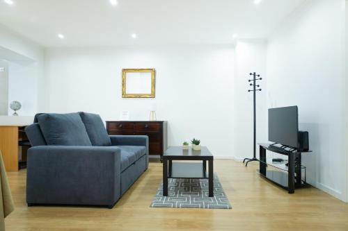 a living room with a blue couch and a tv at Avenida House 1 in Ponta Delgada