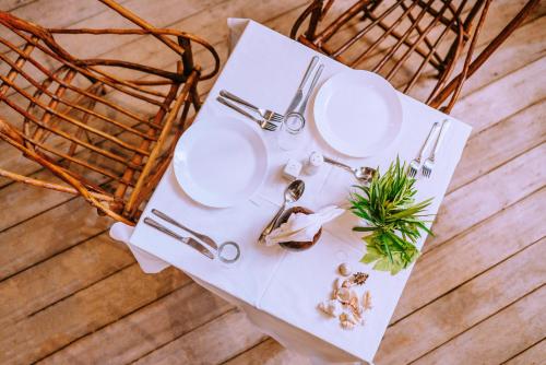 a table with white plates and a basket at La Perla Beach Resort, Zanzibar - Your Beachfront Private Haven in Pwani Mchangani