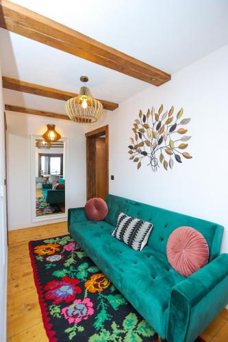 a green couch in a living room with a rug at Conacul Fruntea cu ceru in Iloviţa