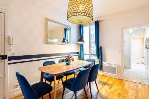 une salle à manger avec une table en bois et des chaises bleues dans l'établissement GuestReady - Bel Apt à deux pas des Champs-Elysées, à Paris