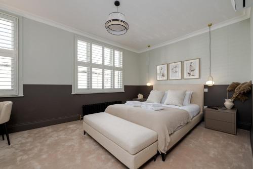 a bedroom with a large white bed and windows at GuestReady - Luxurious home in Archway in London