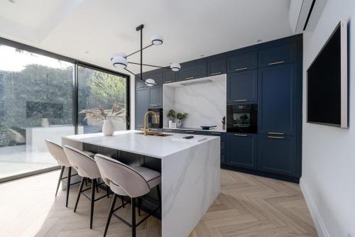 a kitchen with blue cabinets and a large white island at GuestReady - Luxurious home in Archway in London