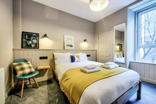 a bedroom with a large bed and a chair at GuestReady - Stylish 2BR in Heart of Tollcross in Edinburgh