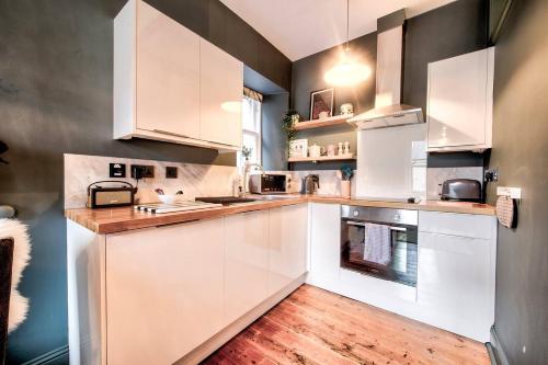 a white kitchen with wooden floors and white cabinets at GuestReady - Stylish 2BR in Heart of Tollcross in Edinburgh