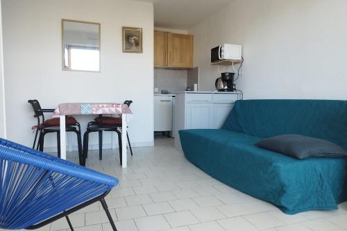 un salon avec un canapé bleu et une cuisine dans l'établissement Near the port and the beach, à Frontignan