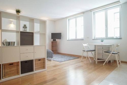 a white living room with a table and a desk at GuestReady - Spacious and Modern Studio in Belém! in Lisbon