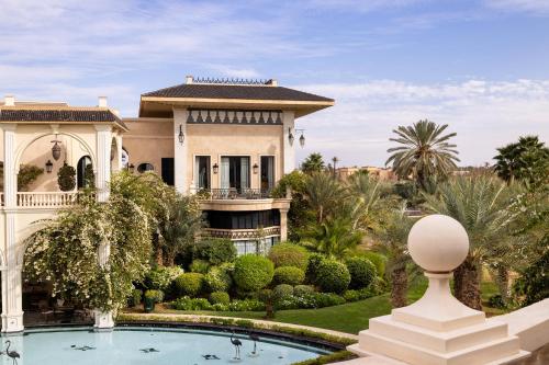 a villa with a swimming pool in front of a house at Palais Ronsard Relais & Chateaux in Marrakech