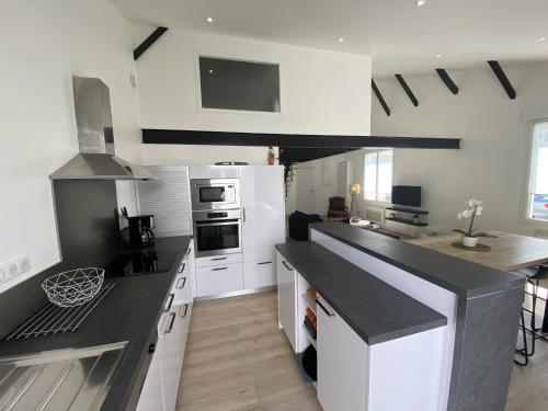 une cuisine avec des armoires blanches et un comptoir noir dans l'établissement Maison style loft plein centre ville, à Les Sables-dʼOlonne