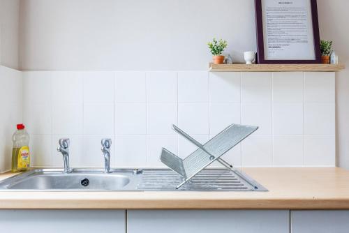 a kitchen sink with a metal sign on it at Bright & Sunny 2BR Near Westcliff Beach & High St by Everhome Ltd in Southend-on-Sea