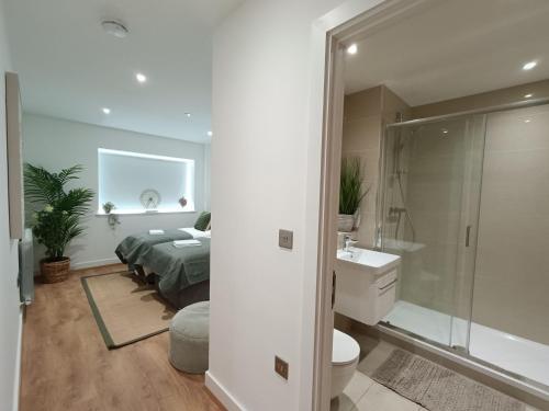 a bedroom with a bed and a bathroom with a shower at Snuggle Inn - Riverside Apartments - Views Over looking London River Thames, Close to O2 Arena, London Excel, London City Airport, Thames Clipper- River Boat Service, Woolwich Ferry, Onsite parking, TWIN ROOM OPTION available in London