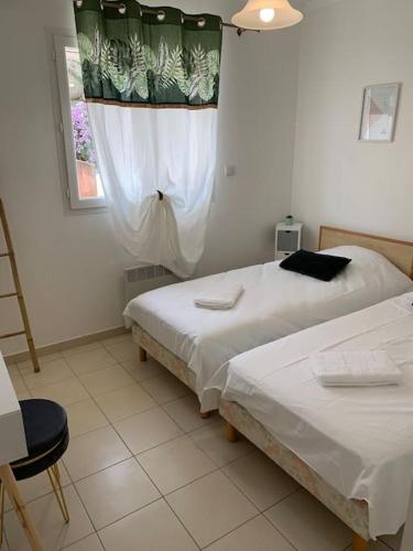 une chambre avec deux lits et une fenêtre et une chaise dans l'établissement Les Cistes Appt type 3 avec terrasse vue sur mer, à Propriano