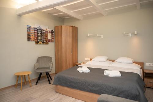 a bedroom with two beds and a chair in it at Tündérkert Apartman in Gyula