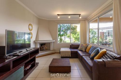 a living room with a couch and a tv at Casa em condo com piscina, a 300m da praia ALI024 in Florianópolis