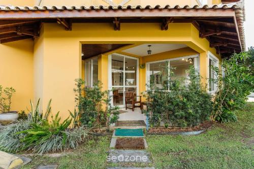 a yellow house with a pathway leading to the front door at Casa em condo com piscina, a 300m da praia ALI024 in Florianópolis