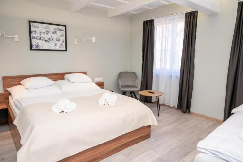 a hotel room with two beds and a chair at Tündérkert Apartman in Gyula