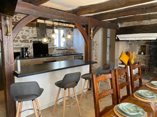 a kitchen with a bar with chairs and a table at Au Charme d Antan Thalamy in Thalamy
