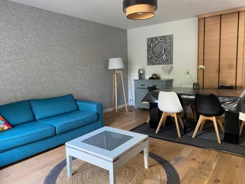 un salon avec un canapé bleu et une table dans l'établissement Maison Familiale- Bassin Arcachon - Au calme, à La Teste-de-Buch