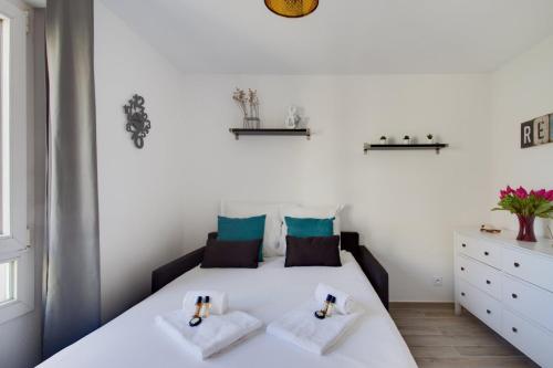une chambre blanche avec un lit avec des serviettes dessus dans l'établissement The Cute Sans-Souci Studio, à Lyon