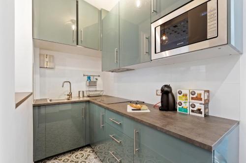 La cuisine est équipée de placards verts et d'un four micro-ondes. dans l'établissement GuestReady - Nice apartment for 6 in Paris, à Paris