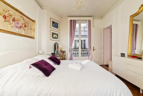 une chambre avec un grand lit blanc avec des oreillers violets dans l'établissement GuestReady - Appartement Vintage dans Le Marais, à Paris