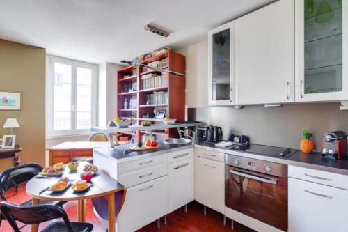 une cuisine avec des armoires blanches et une table à l'intérieur dans l'établissement GuestReady - Beau séjour dans Le Marais, à Paris