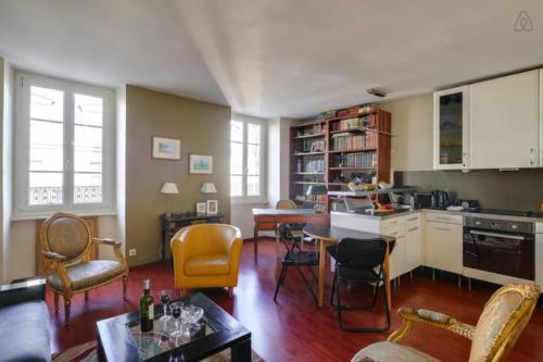 un soggiorno con tavolo e sedie e una cucina di GuestReady - Amazing Le Marais Flat - 2 mins to Hôtel de Ville a Parigi