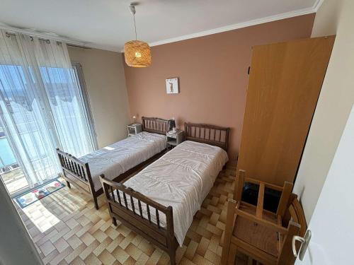 une chambre avec deux lits et une grande fenêtre dans l'établissement Port-la-Nouvelle - Appartement traversant 6 couchages avec balcons, parking et proche plage - FR-1-229C-47, à Port-la-Nouvelle