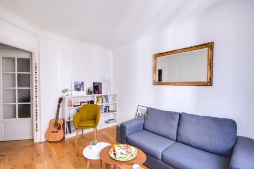 een woonkamer met een blauwe bank en een gitaar bij GuestReady - Modern flat near Place De La Bastille in Parijs