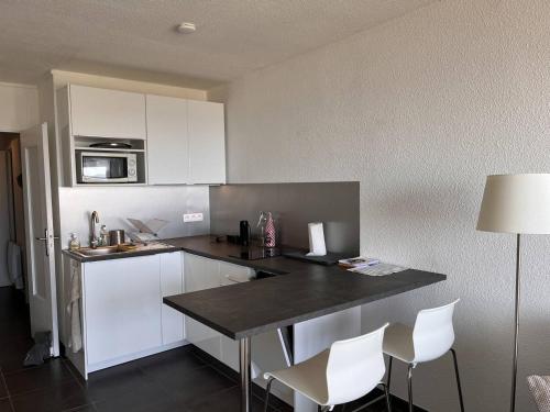 une cuisine avec des armoires blanches et un comptoir noir dans l'établissement Studio Cabine 4 pers, parking privé, direct plage - FR-1-559-37, à Palavas-les-Flots