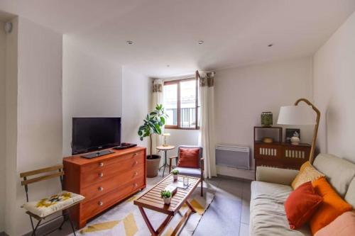 ein Wohnzimmer mit einem Sofa und einem TV in der Unterkunft GuestReady - Charming Flat - 6 mins to Gare Du Nord Metro in Paris