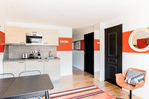 cocina con mesa y paredes de color naranja y blanco en GuestReady - Modern Apt in Issy-les-Moulineaux, en Issy-les-Moulineaux